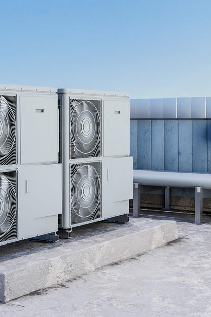 Rooftop HVAC condensers with fans on a platform beside a blue wall, with light snow.