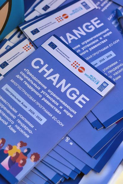 Blue flyers about CHANGE laid on a blue surface, showing event details and colorful icons.