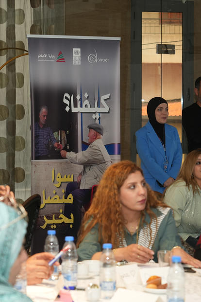 Group of women in hijabs seated around a long table with plates and drinks at a community event.