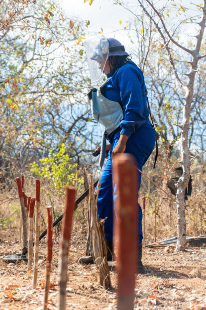 Person dressed in blue holding detector finding landmines
