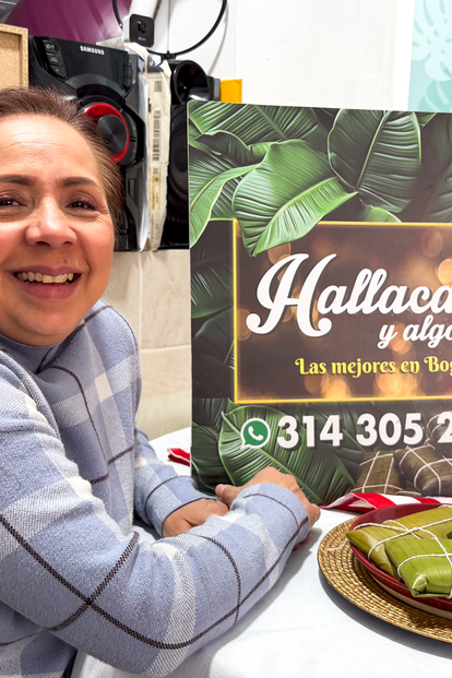 Smiling woman at a deli counter with a Hallacas sign in the background.