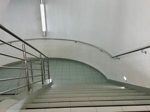 A view of a curved staircase with stainless steel railing and white walls.