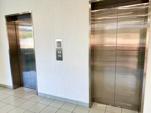 Two elevator doors in a bright hallway with tiled flooring.