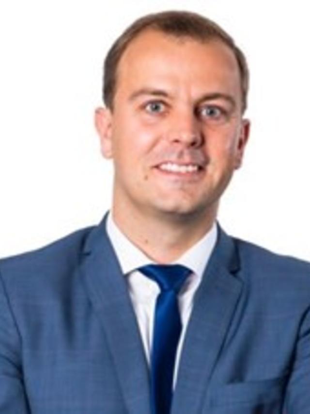 a man wearing a suit and tie smiling at the camera