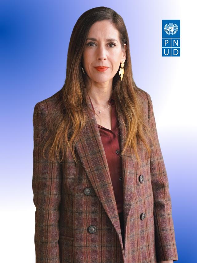 Woman in brown plaid blazer and burgundy top, blue gradient background with UNDP logo.