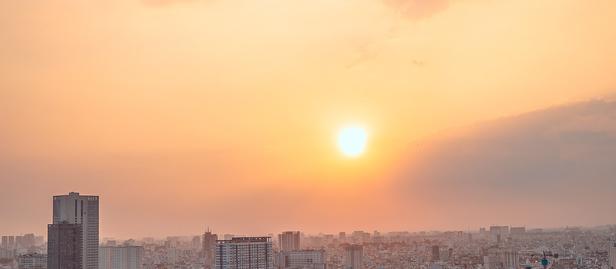 Photograph: Sunset over a city skyline along a river, boats and reflections on the water.