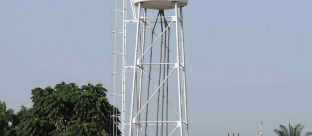 Water tower on a metal lattice with palm trees and blue sky; UNDP Côte d'Ivoire branding.