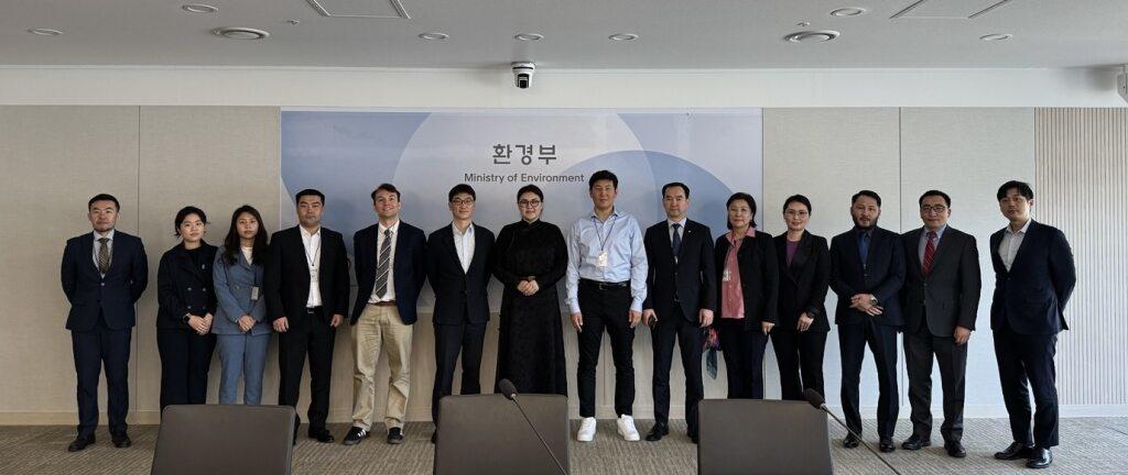 Group of professionals posing together in an office setting, smiling at the camera.