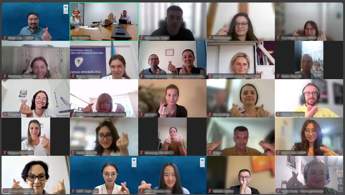 Grid of participants in a virtual meeting, all showing thumbs up with smiles.