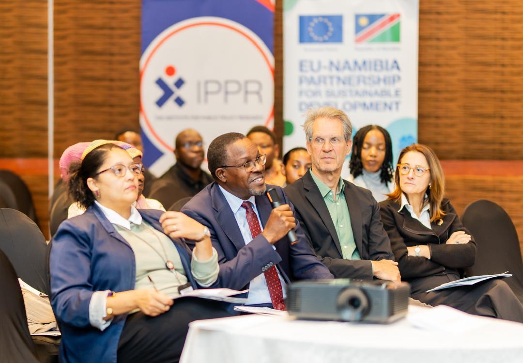 A group of attendees engages in discussion at a conference, with banners in the background.