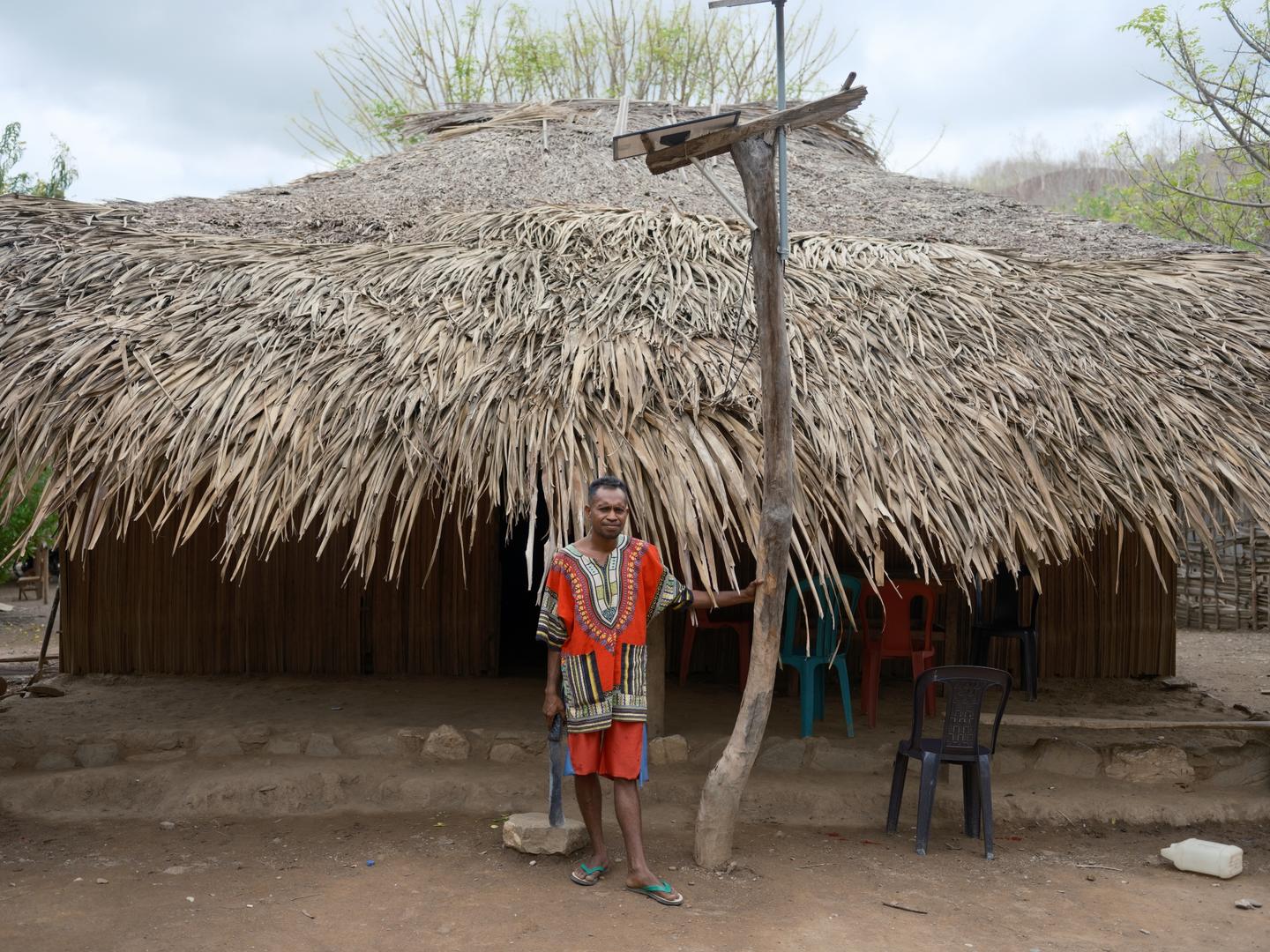 Manuel stands before his traditional home in the sub-village of Bua, where solar panels mounted above have transformed daily routines for his family  to feel more secure after dark. | UNDP BRH/Kapil Das