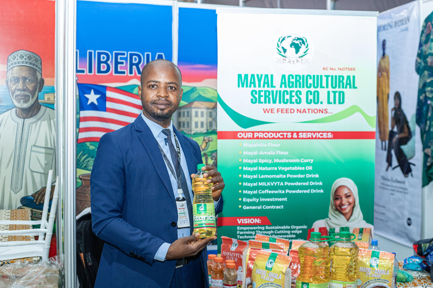 Man in blue suit at Mayal Agricultural Services Co. Ltd booth with product packages on display.