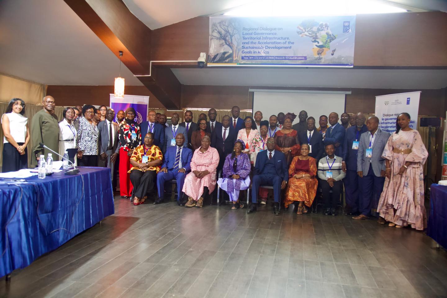 Group of people in a conference hall posing for a group photo beside blue-draped tables.