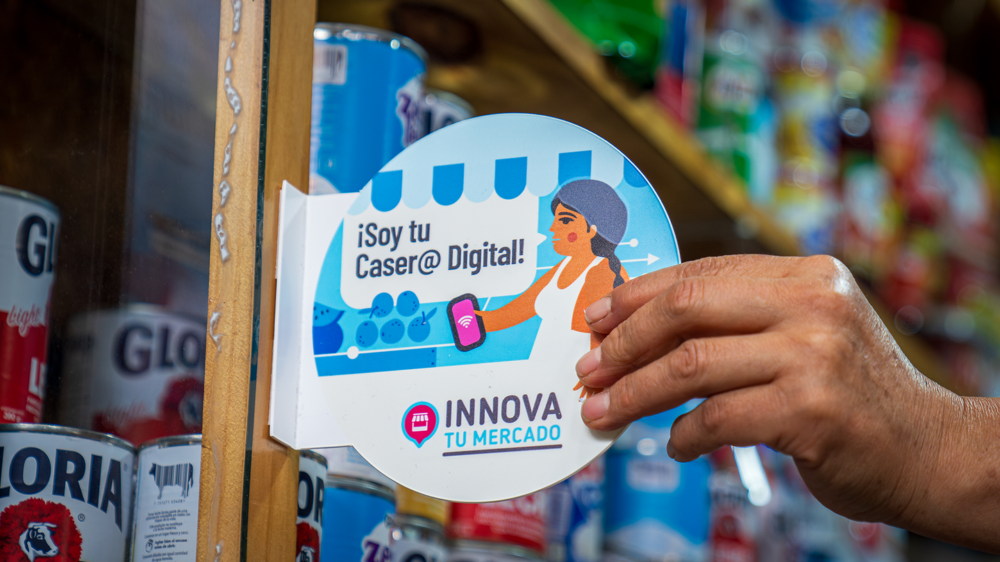 Close-up of a hand pointing at a blue and white product label on a store shelf.