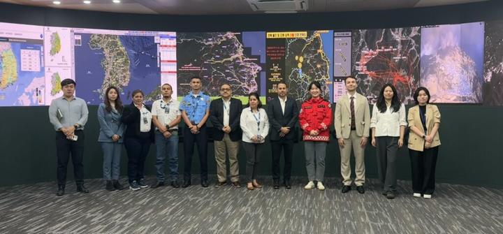 A group of diverse individuals stands in front of large displays in a meeting room.