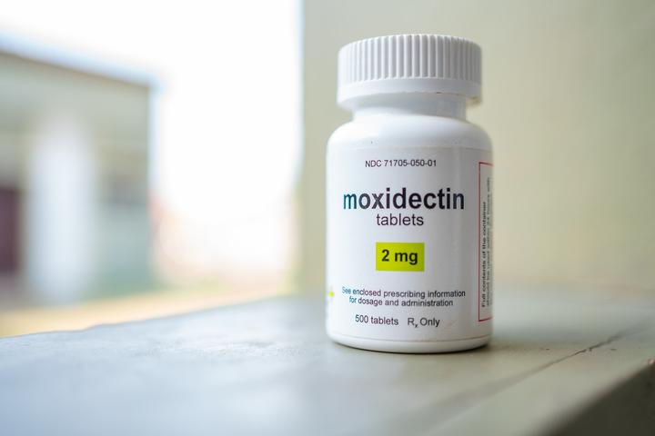 Photograph of a white bottle labeled moxidectin tablets 2 mg on a windowsill.