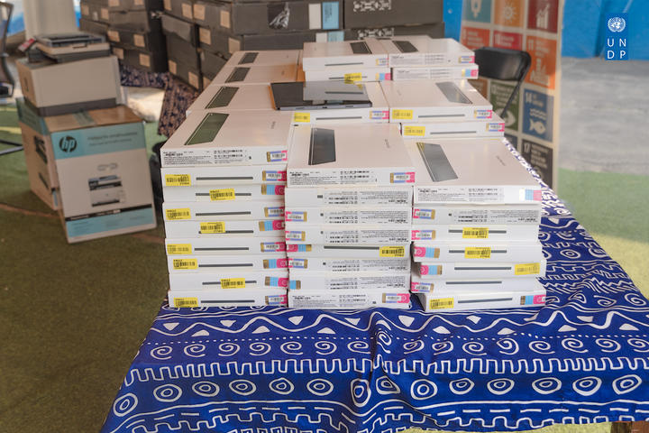 Photograph of stacks of white boxes on a blue patterned tablecloth in a warehouse.
