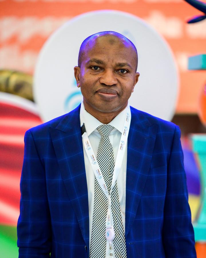Portrait of a man in a blue checkered blazer and tie, against a colorful backdrop.