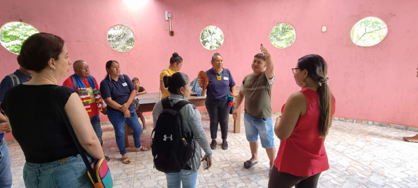 Group of people standing in a circle in a pink-walled room with circular wall decorations.